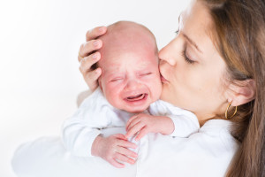 Young Mother Kissing Her Crying Newborn Baby