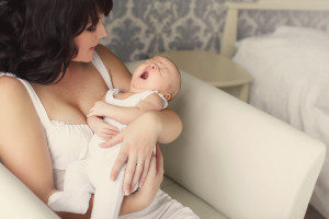 Young mother holds a baby yawning in her sleep.