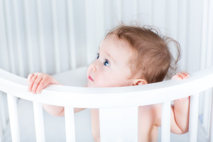 Adorable Little Baby Standing In A Beautiful Round White Crib On A Sunny Morning