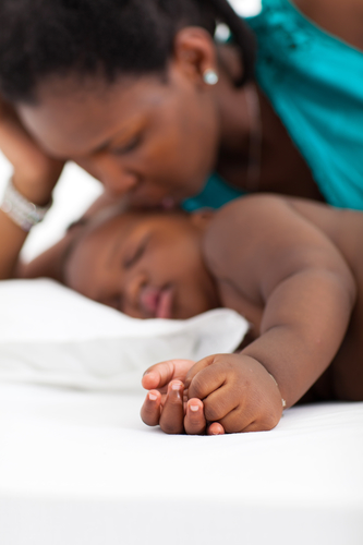 african american mother kissing sleeping baby