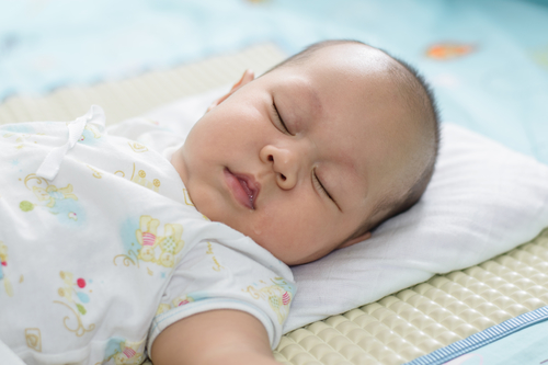 Asian babies sleep on white linen.