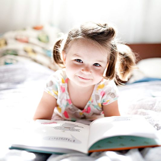 CHILDHEADERpreschool-girl-lies-on-a-bed-in-soft-window-light-reading-books_t20_yv4YOp-1-scaled